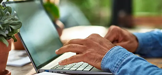 Close up of man's hands typing on laptop keyboard.
