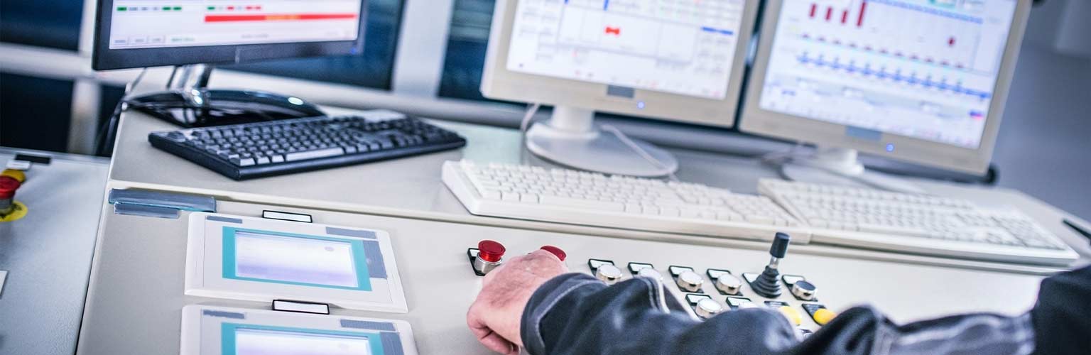 A man controlling a workstation with three screens