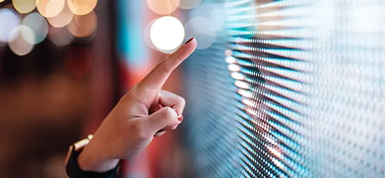 Close-up of female finger touching futuristic LED display board.