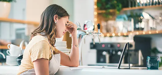 A young woman experiencing stress while working in a cafe.