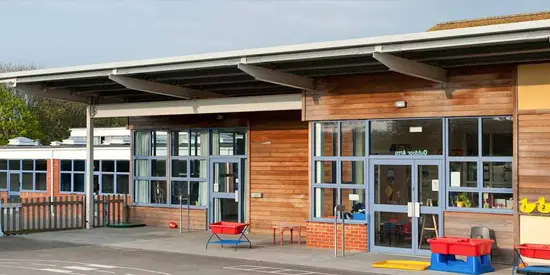 Exterior of a modern school building with large windows and playground equipment outside