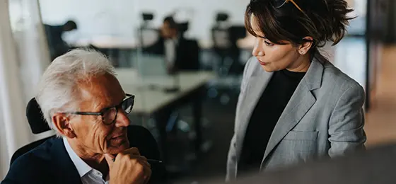 Senior businessman discussing strategy with female colleague in office.