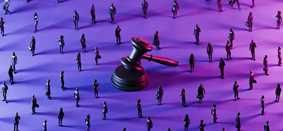 Judge's gavel in the centre of the image surrounded by small figurines representing people.