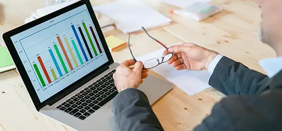 Business person looking at a bar chart on a laptop.