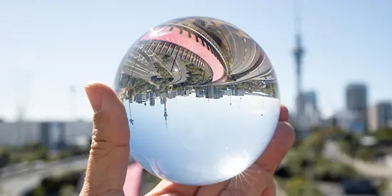 Hand holding crystal ball in front of motorway and cityscape