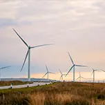 A sunset in the Scottish highlands with renewable energy wind turbines far into the horizon