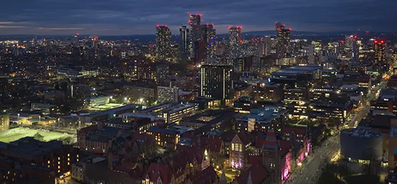 Manchester city skyline at night showing Oxford Road in the foreground.