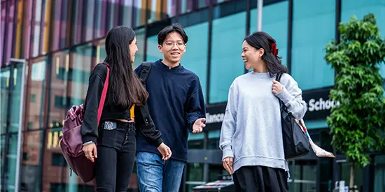 Three masters students walking outside Alliance MBS building.