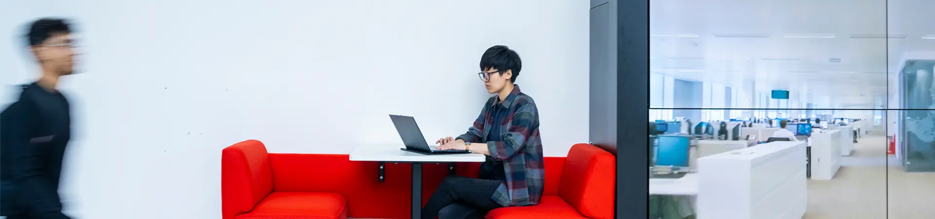 A student working on a laptop in an informal study space at Alliance MBS.