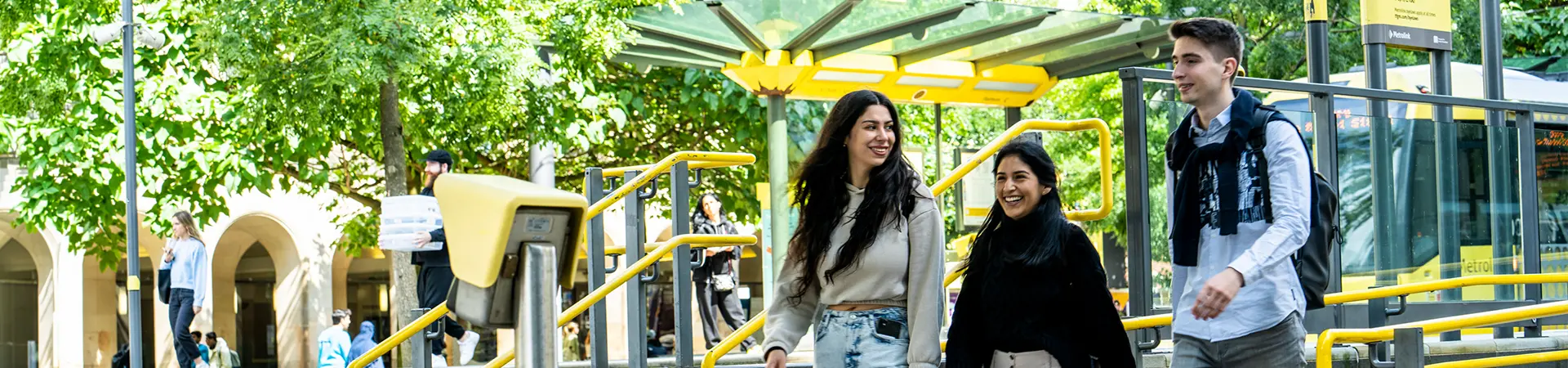 Three masters students walking next to a tram stop in central Manchester.