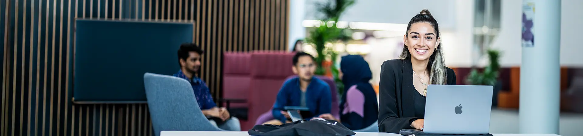 A female student working on her laptop at AMBS.