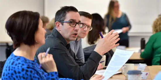 Three professional apprentices having a group discussion in a classroom