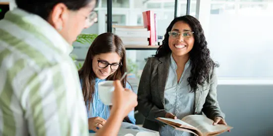 A group of PhD business students studying and chatting at the library