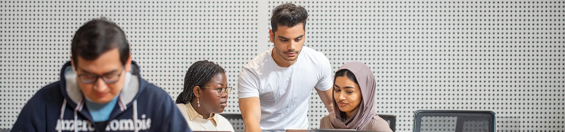 Three students working together in a classroom.