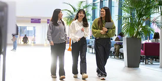 Three female students walking through AMBS.