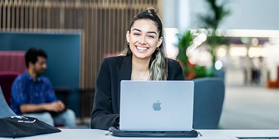 A female student working on her laptop at AMBS.