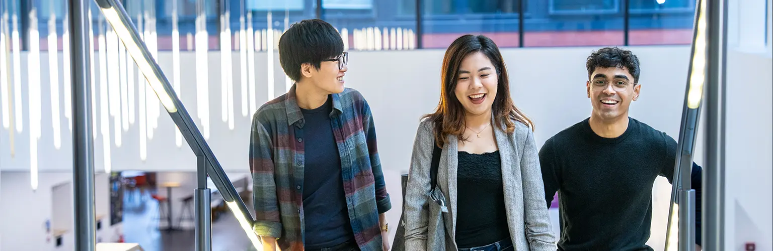 Alliance MBS students walking together inside the business school building, smiling and talking.