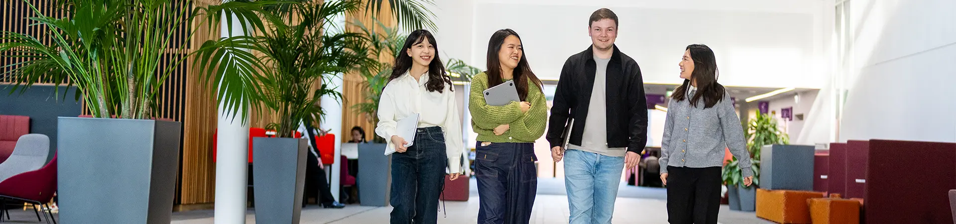 Four students walking through a large open study space at Alliance MBS.