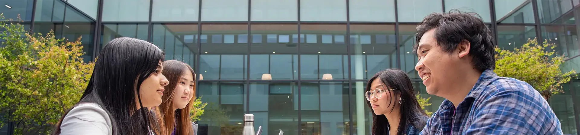 Four students sitting at a table outside AMBS.