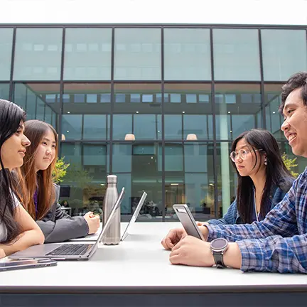 Alliance MBS students sitting outside in discussion during a group activity on campus.
